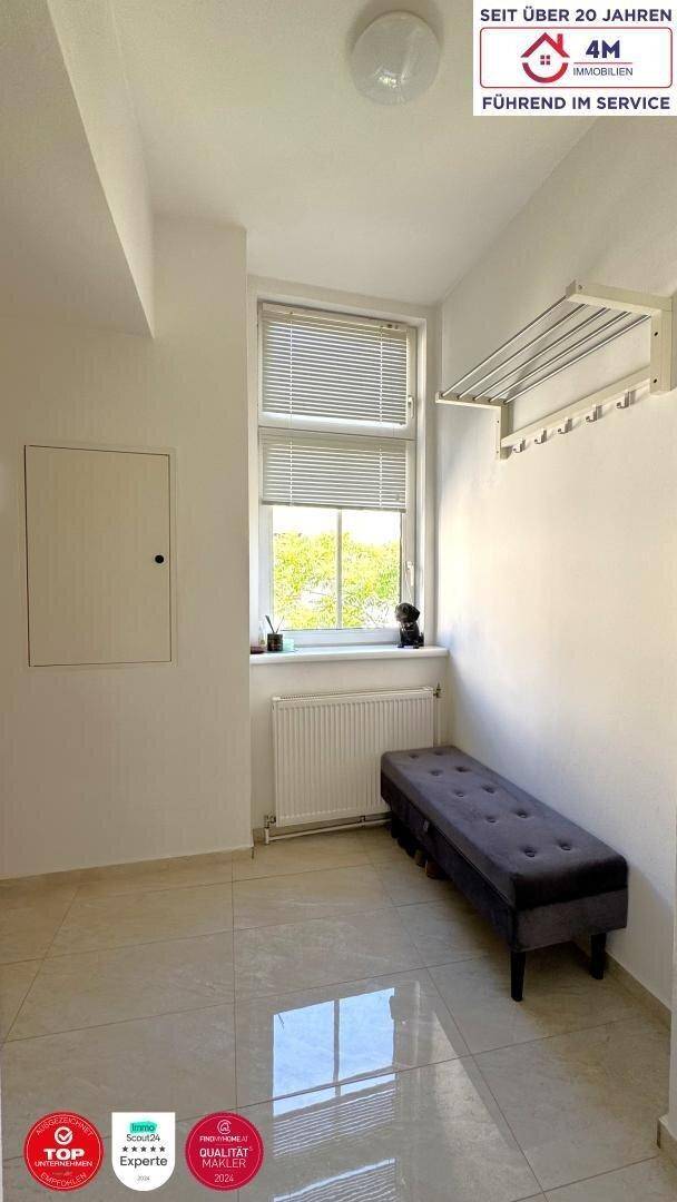 Heller Flur oder Eingangsbereich mit Fliesenboden, Fenster und einer praktischen Sitzbank.
