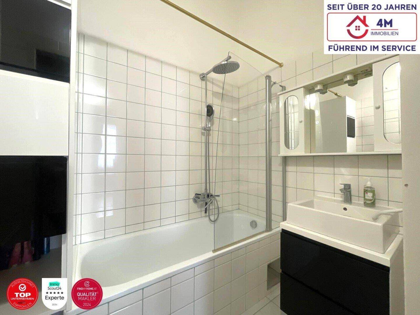 Modernes Badezimmer mit Badewanne, Duschfunktion, Spiegelschrank und weißen Fliesen.