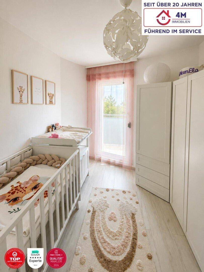 Helles Kinderzimmer mit Babybett, Wickeltisch und Zugang zu einem kleinen Balkon.