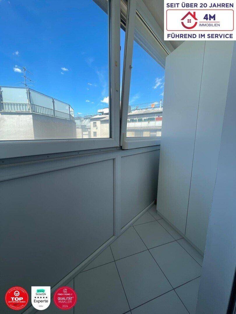 Verglaster Balkon mit Fliesenboden und Blick auf die umliegenden Gebäude.