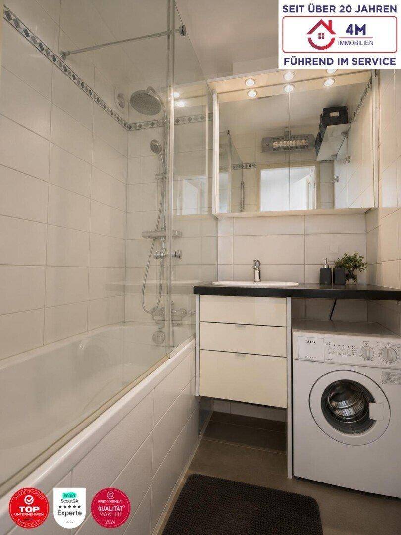 Modernes Badezimmer mit Badewanne, Duschabtrennung, Waschbecken und Waschmaschine.