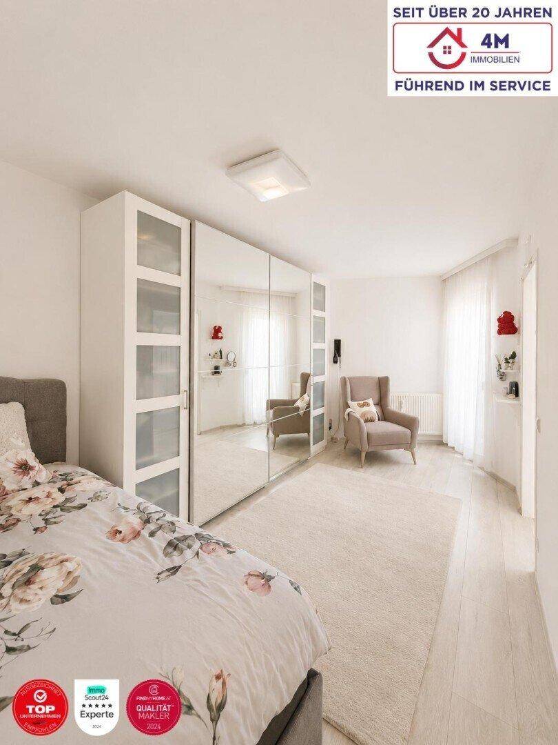 Schlafzimmer mit großem Spiegelschrank, gemütlichem Sessel und hellem Laminatboden.
