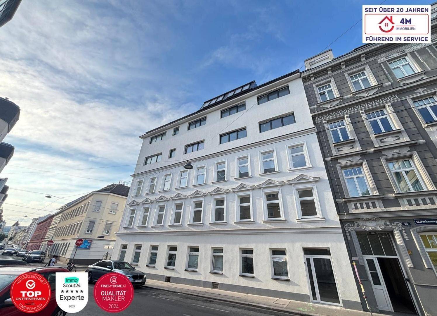 Moderne Fassade eines Mehrfamilienhauses mit vielen Fenstern und klassischer Architektur in der Stadt.