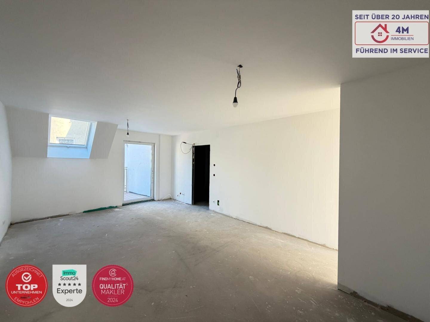 Großer, unfertiger Raum mit weiß gestrichenen Wänden und einem Dachfenster, bereit für den Ausbau.