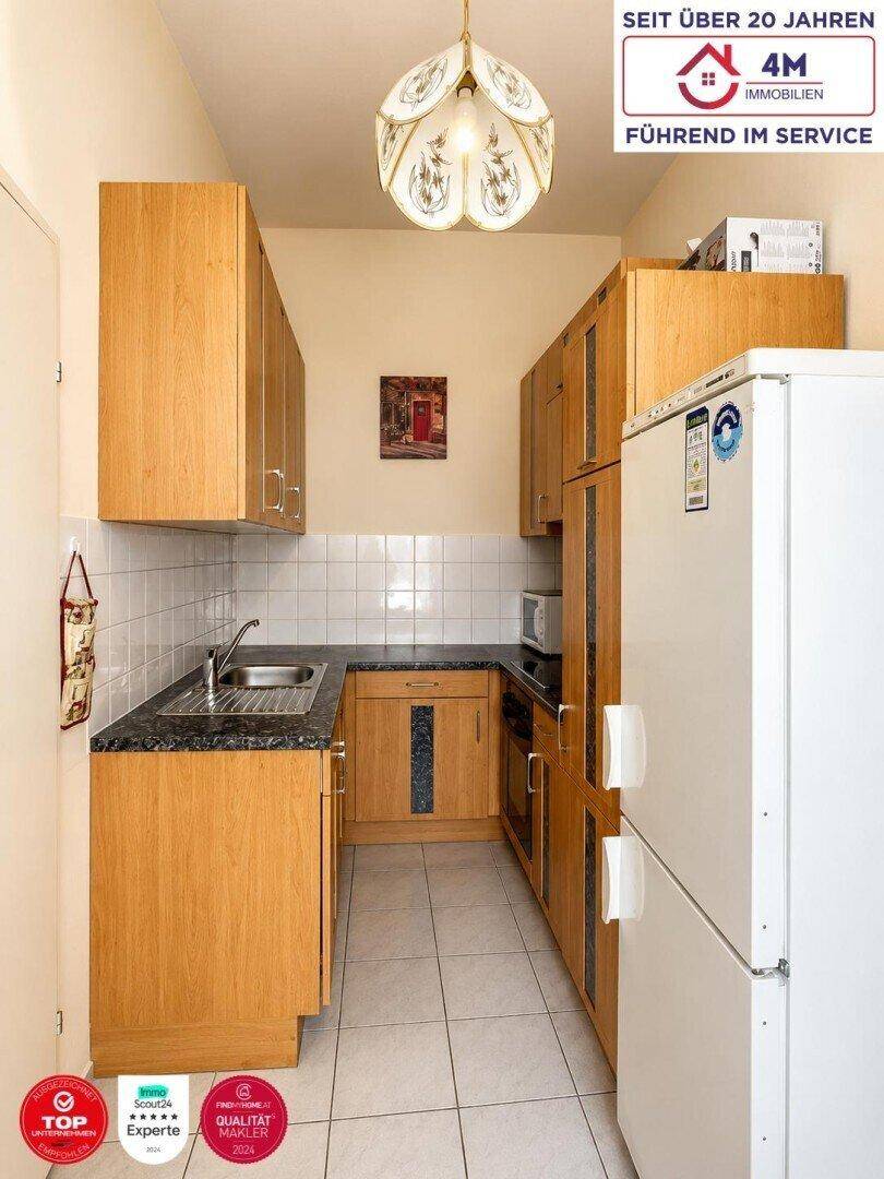 Funktionale Küche mit Holzschränken, Fliesenboden und integrierten Geräten.