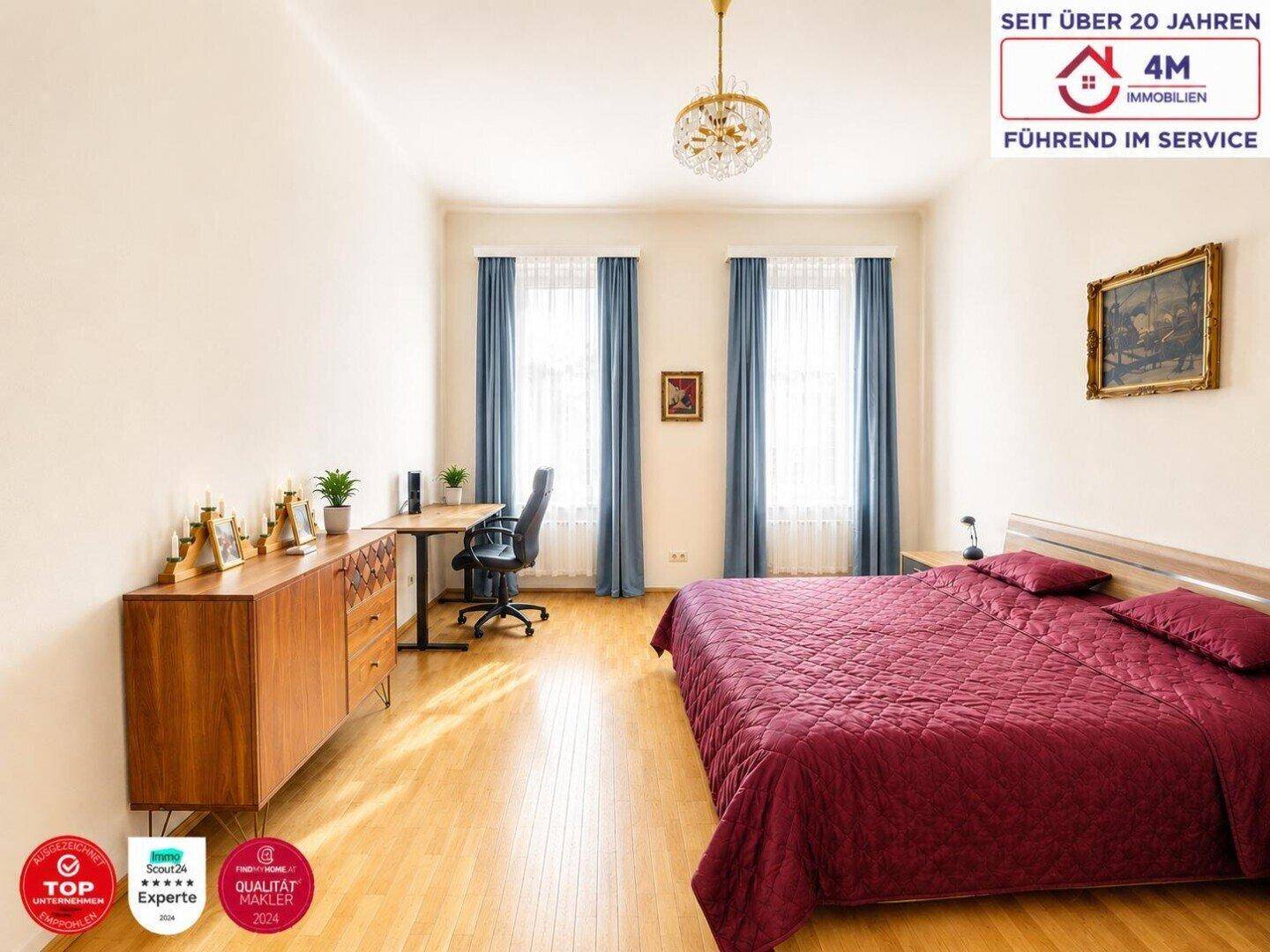 Helles Schlafzimmer mit Holzboden, großem Bett und Arbeitsbereich am Fenster.