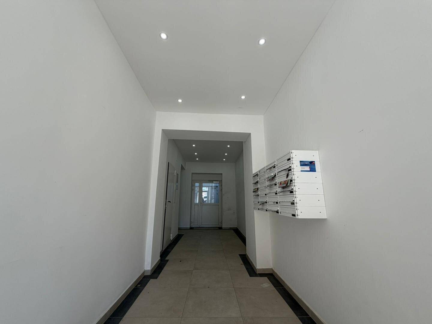 Heller Eingangsbereich mit modernen Einbaustrahlern und Briefkästen, sauber und gepflegt.