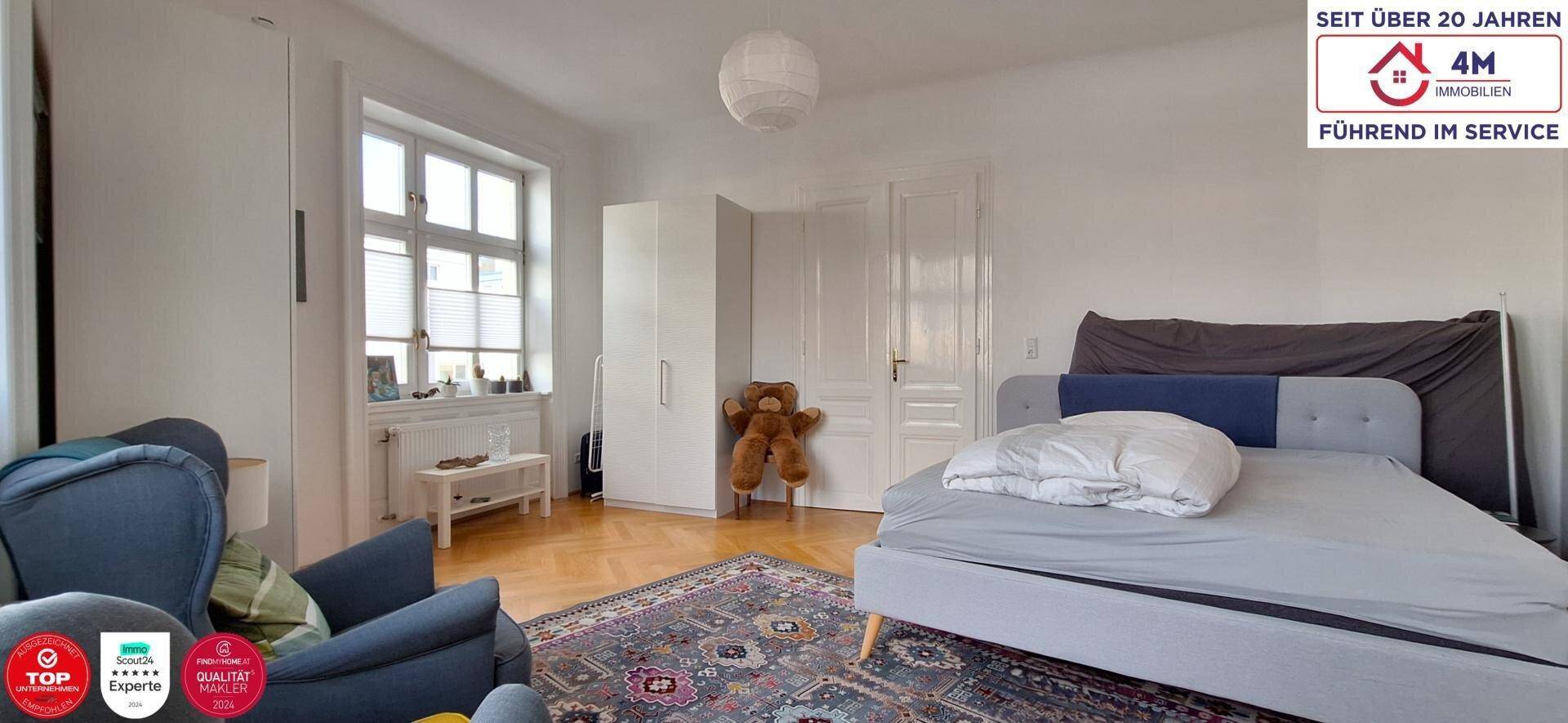 Helles Schlafzimmer mit Parkettboden, großem Fenster und schlichtem Design.
