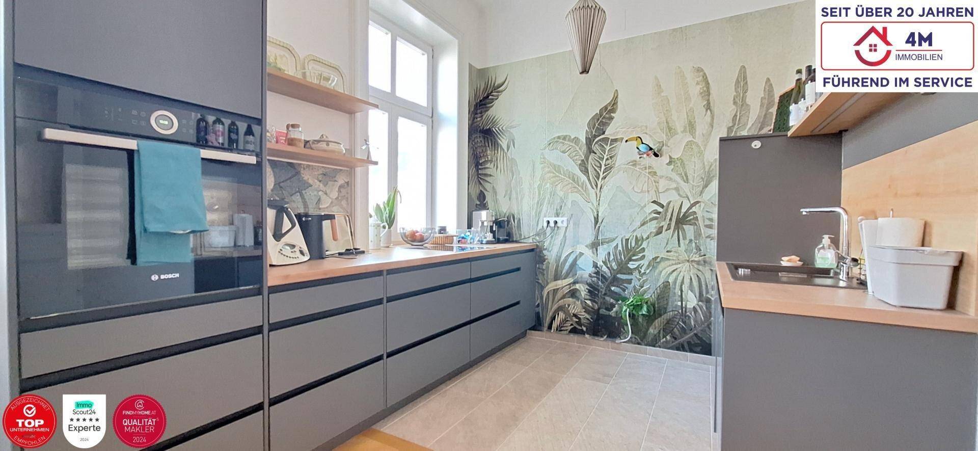 Moderne Einbauküche in Grau mit integrierten Geräten und dekorativer Wandtapete.