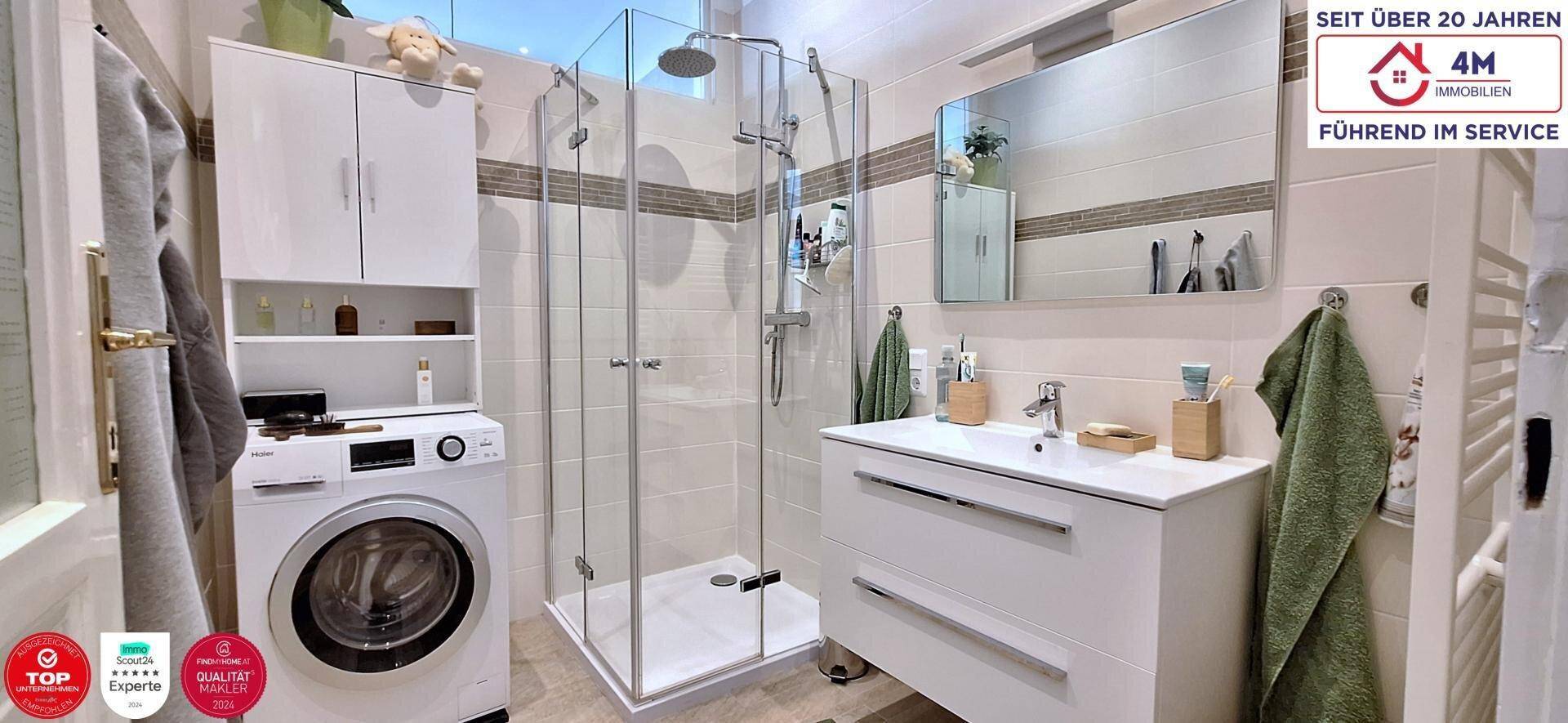 Modernes Badezimmer mit Duschkabine, Waschmaschine und weißem Waschtisch.