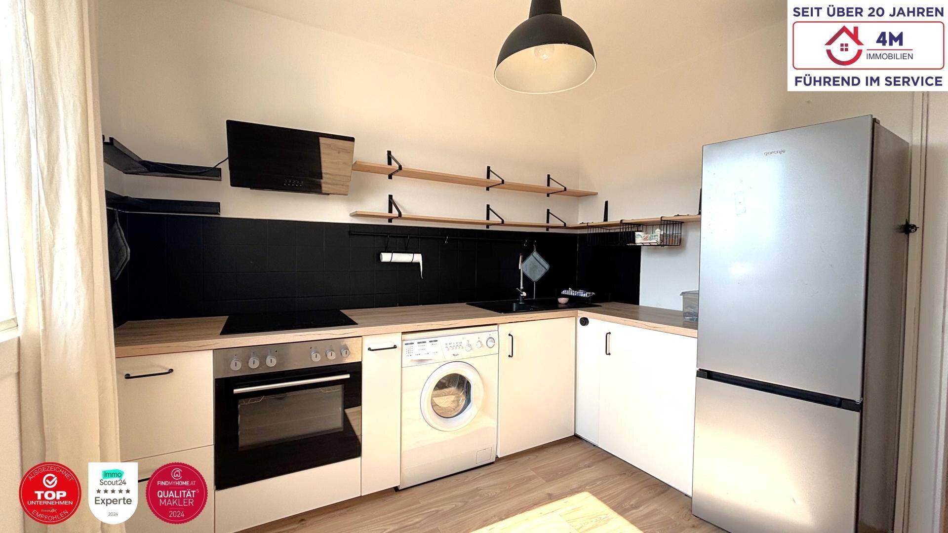 Funktionale Küche mit weißen Schränken, Holz-Arbeitsplatte und integrierten Geräten.