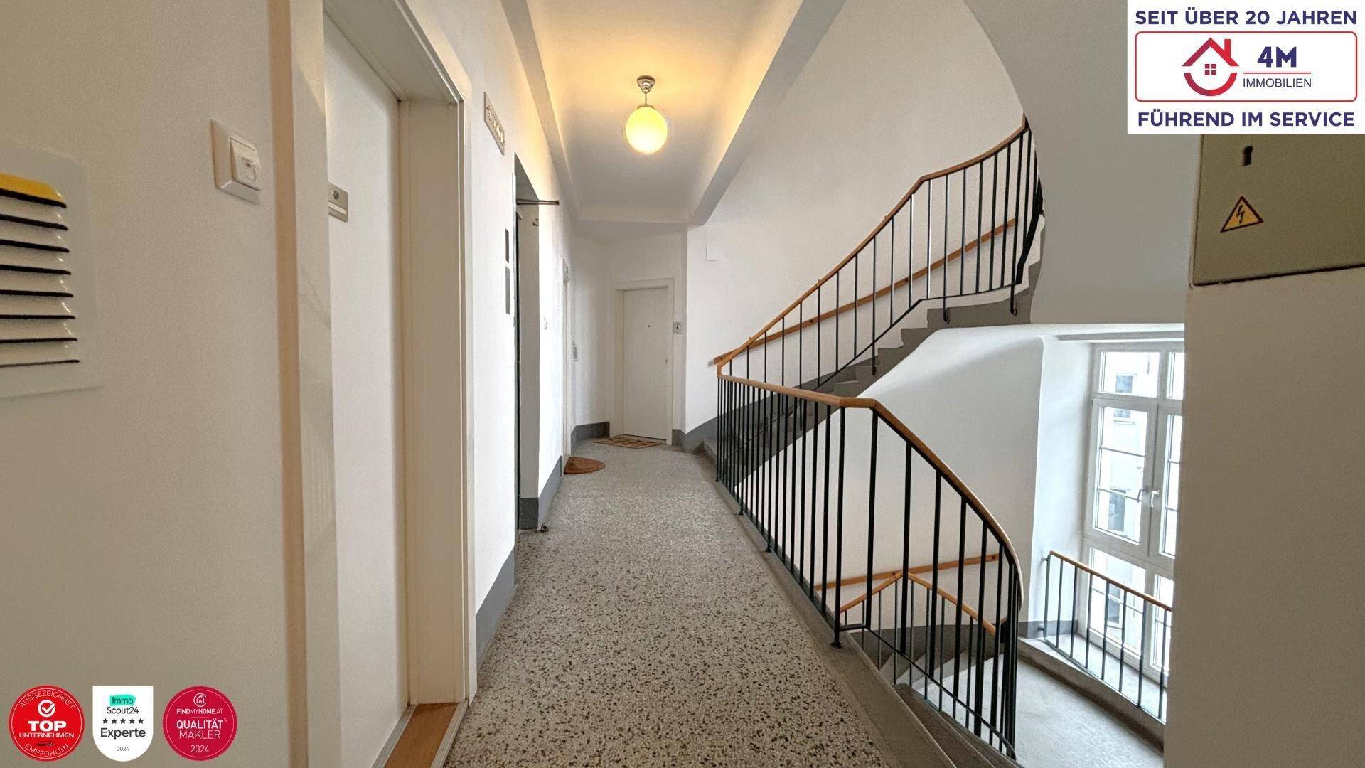 Gemeinschaftlicher Treppenaufgang in einem Altbau mit Terrazzoboden und klassischem Geländer.