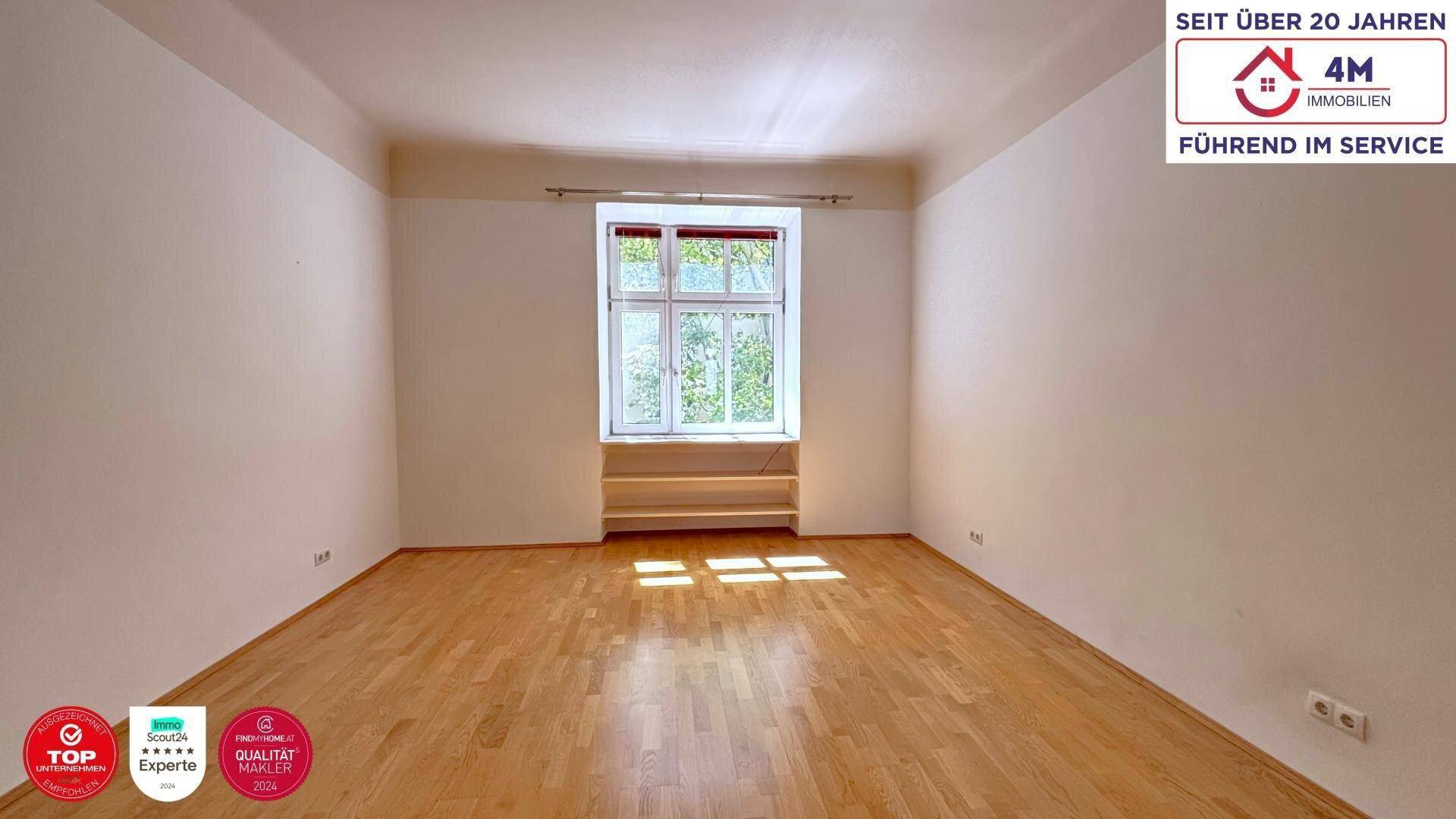 Geräumiges Zimmer mit Holzboden und einem großen Fenster, das den Raum erhellt.
