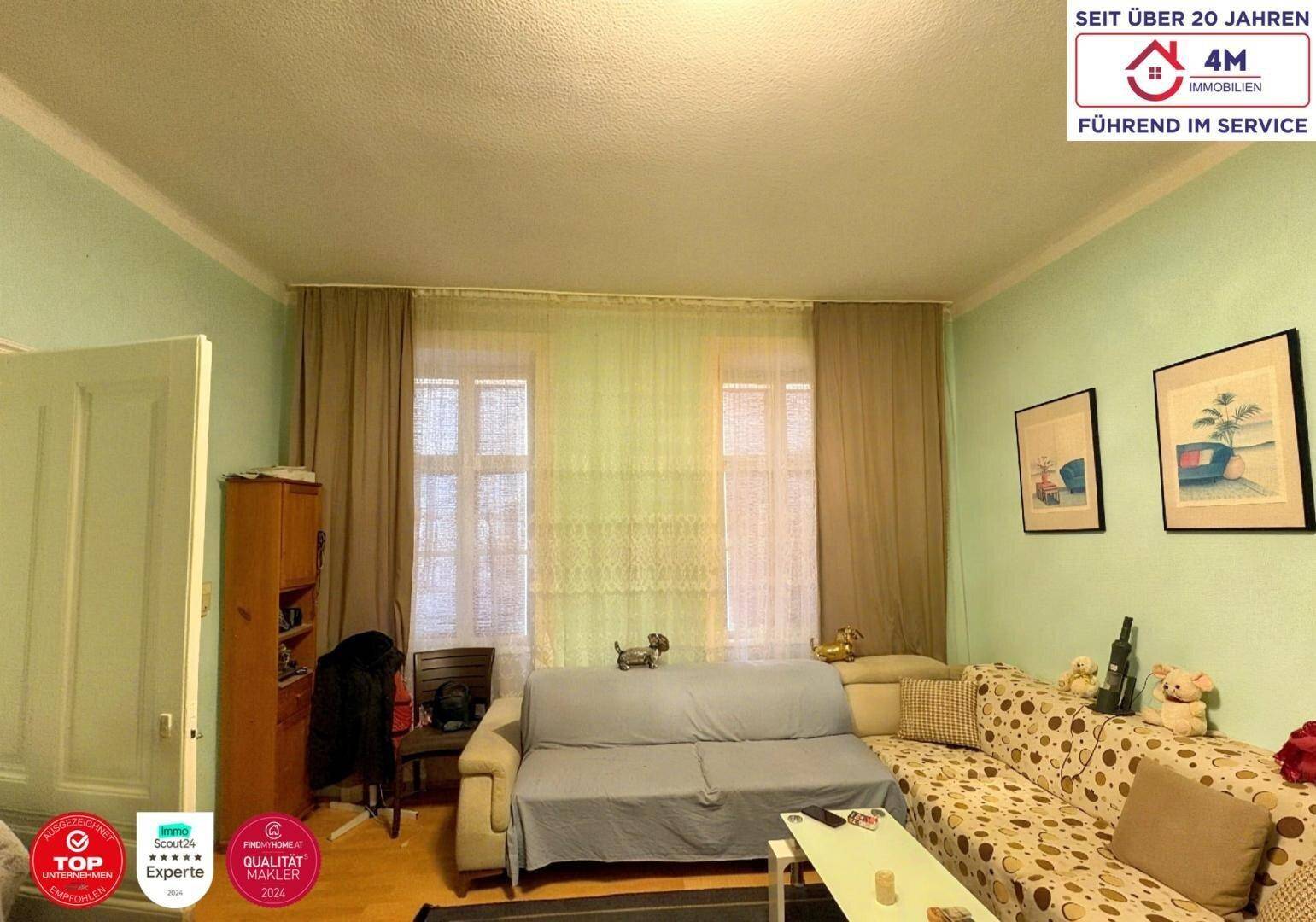 Wohnbereich mit zwei Fenstern, Sofa und Vorhängen, bietet natürliches Licht.