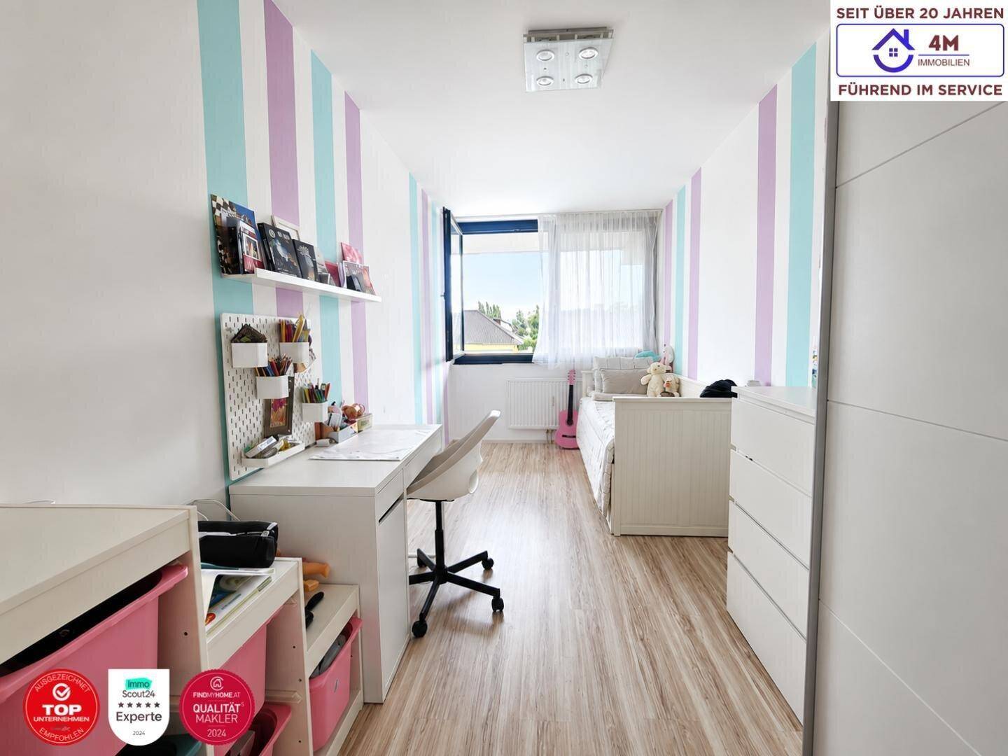 Kinderzimmer mit farbigen Streifenwänden, Schreibtisch und hellem Boden.