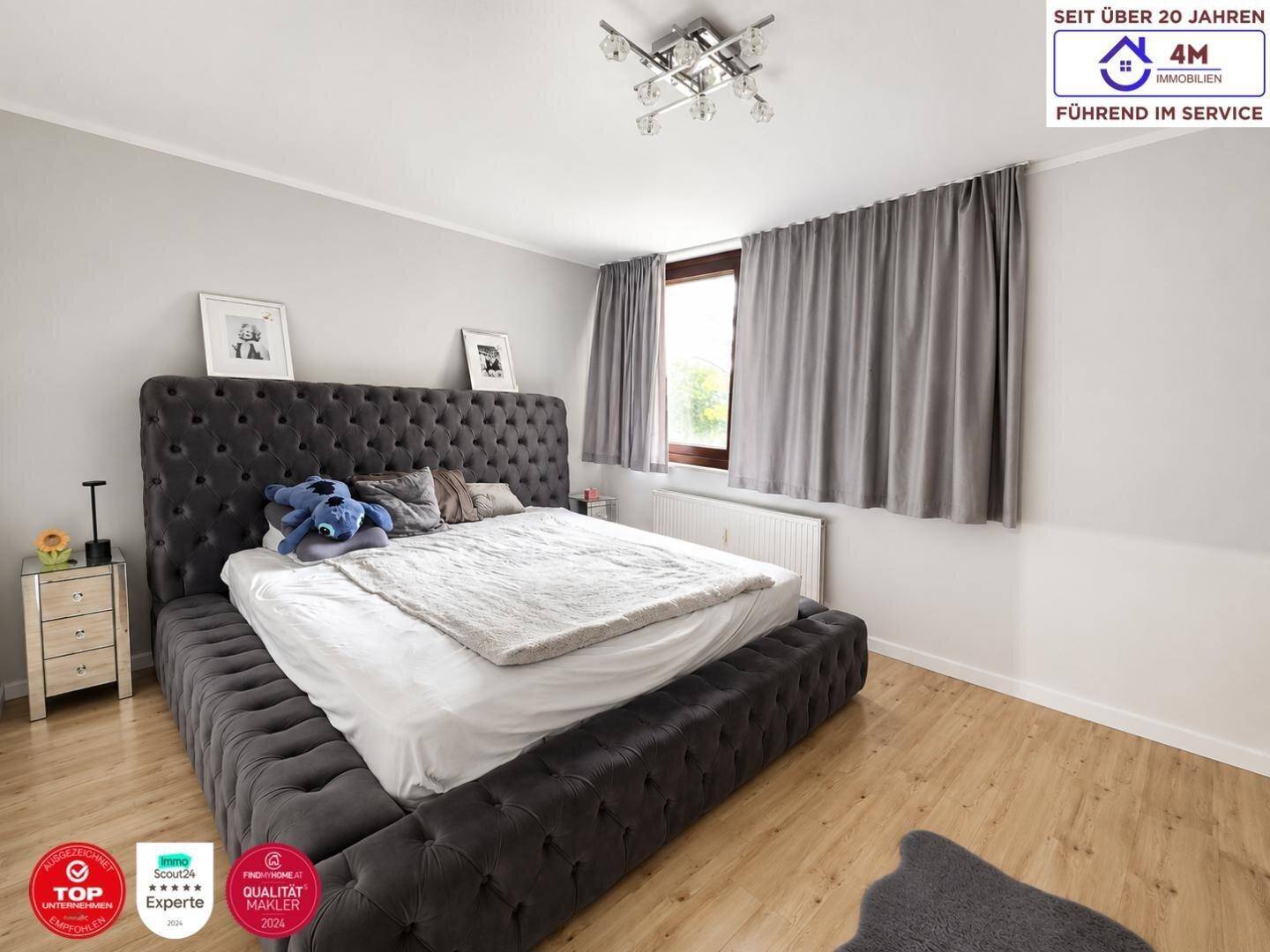 Geräumiges Schlafzimmer mit großem Polsterbett und Holzfußboden.