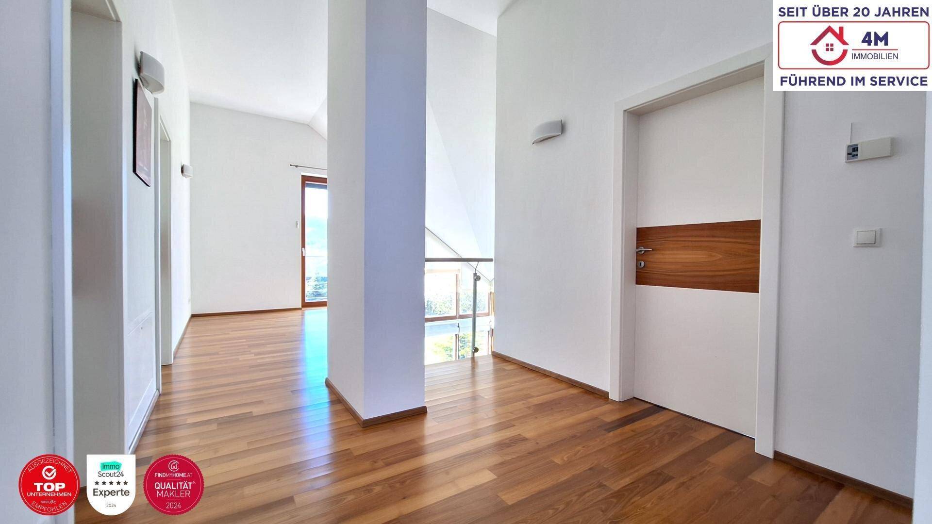 Heller Flur im Obergeschoss mit Holzboden und Blick auf die untere Etage.