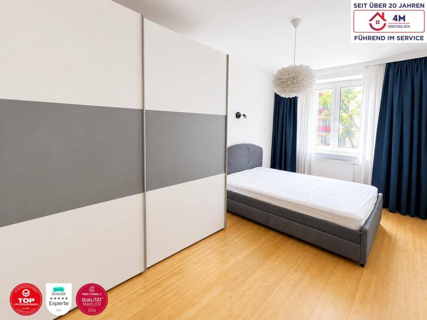Gemütliches Schlafzimmer mit Holzboden, großem Fenster und modernem Kleiderschrank.