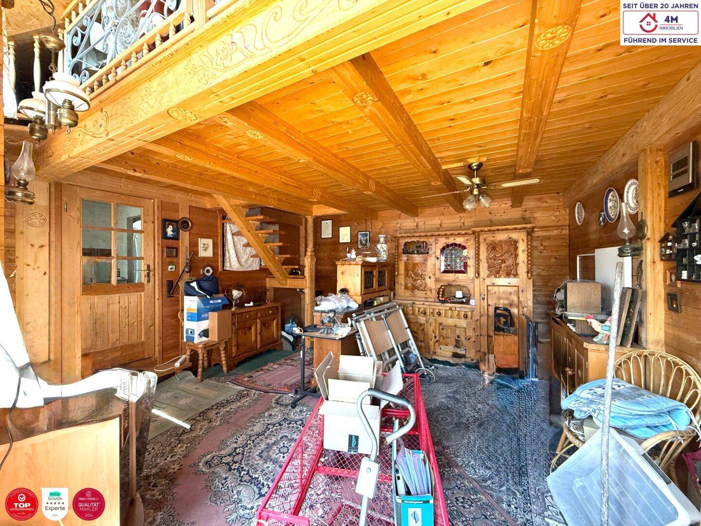 Rustikaler Innenraum mit Holzwänden und -decken, gefüllt mit traditionellen Möbeln und Teppichen.