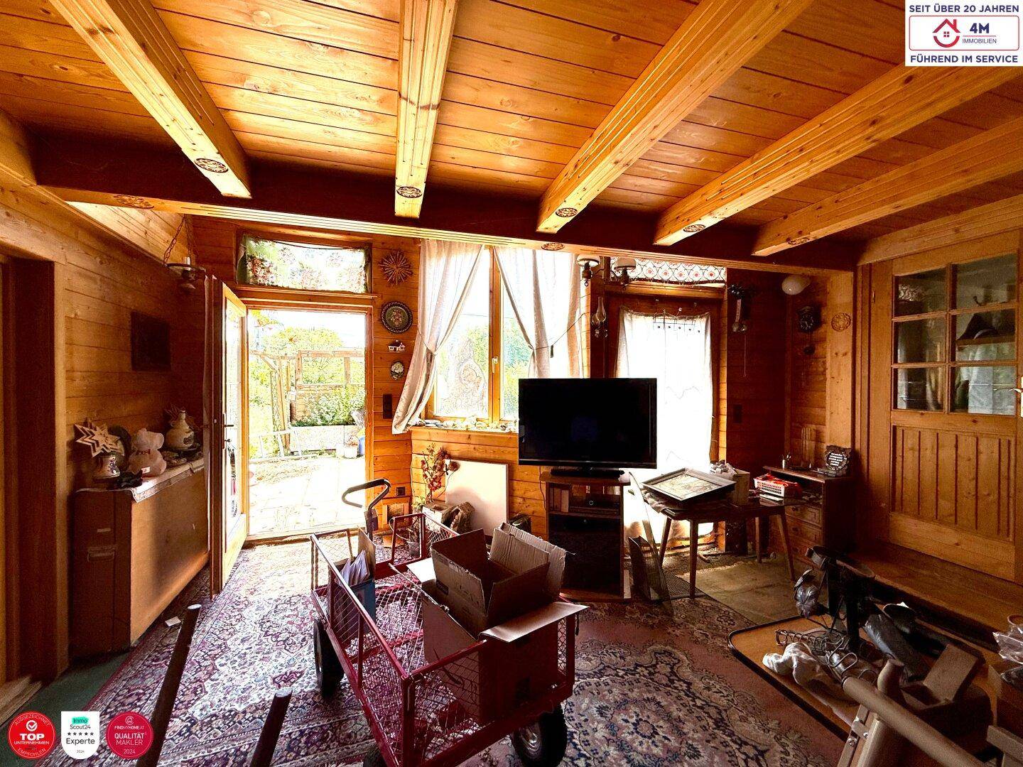 Gemütlicher Wohnbereich mit viel Holz, einem Fernseher und direktem Zugang zum Garten.