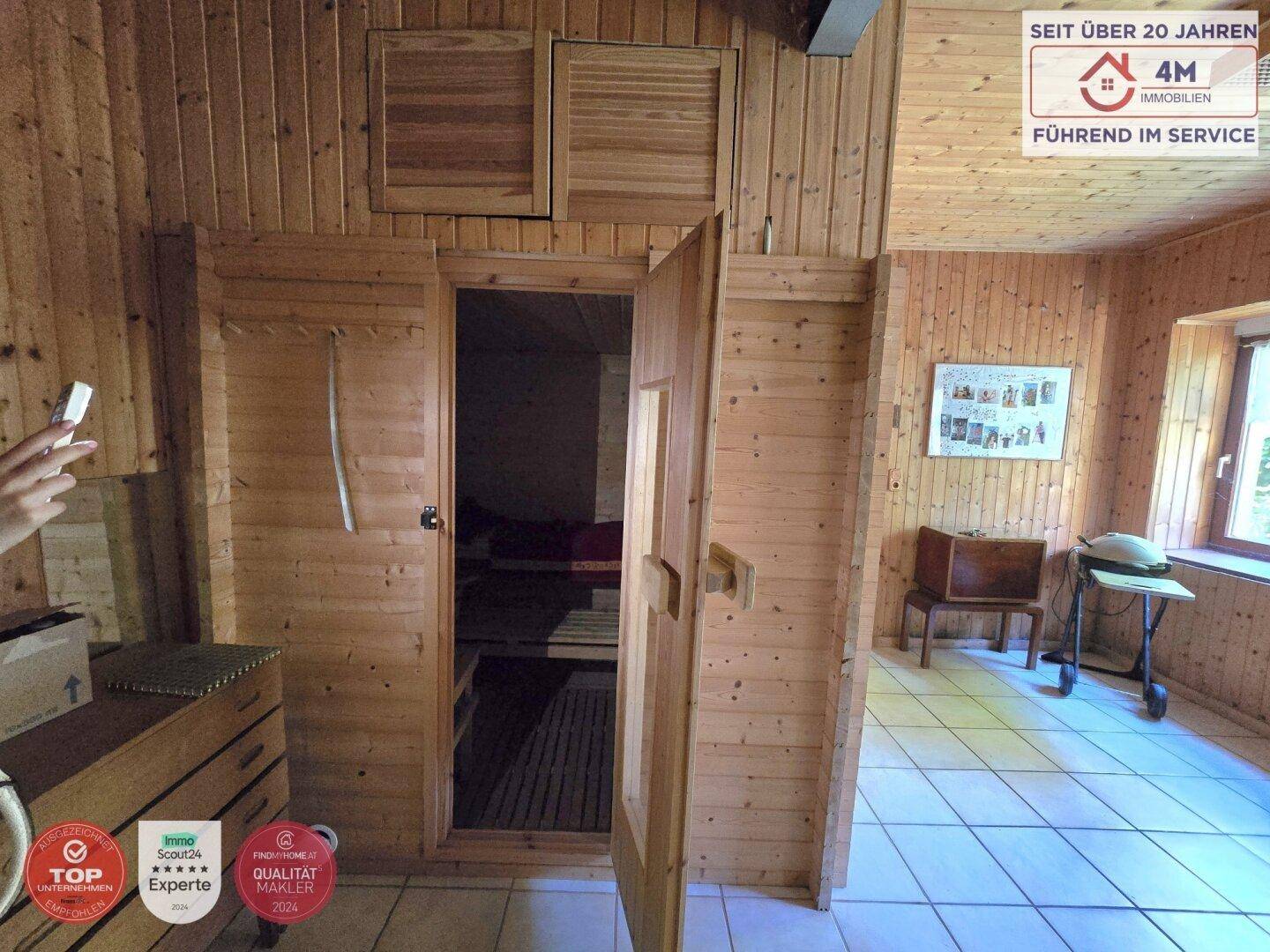Holzvertäfelte Sauna mit Bänken und Fliesenboden, Teil eines Wellnessbereichs.