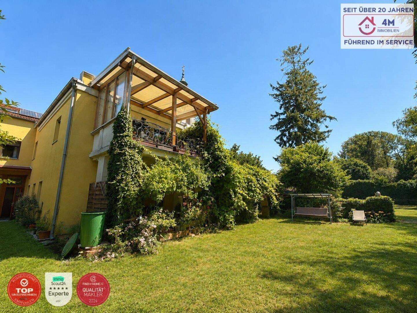 Rückseite des Hauses mit überdachtem Balkon und großem, gepflegtem Gartenbereich.