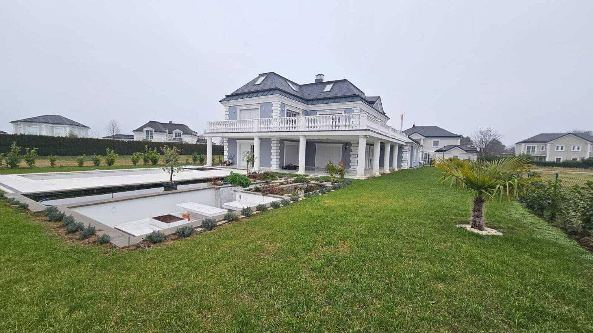 Weitläufiger Gartenbereich der Villa mit großem Pool und gepflegter Rasenfläche in ländlicher Umgebung.