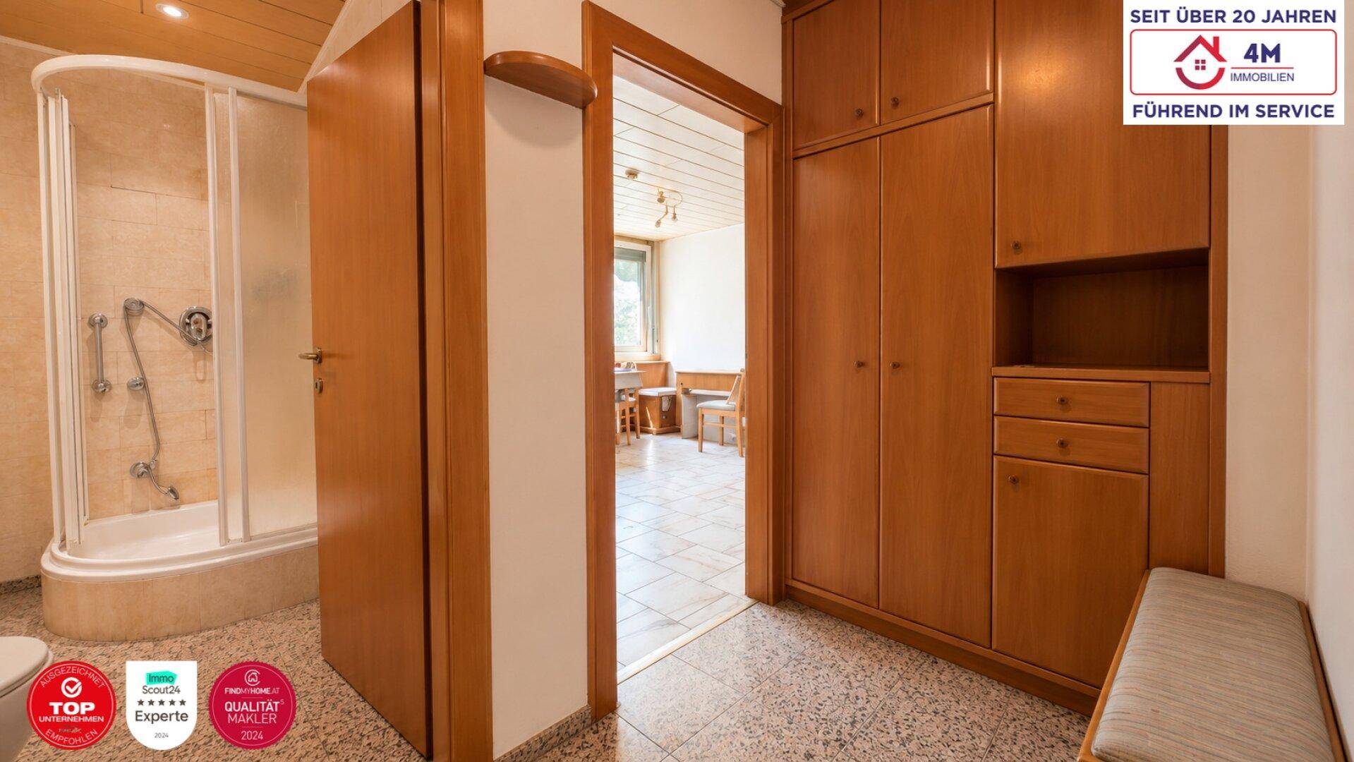Flur mit praktischen Einbauschränken und Blick in ein Badezimmer mit Dusche.