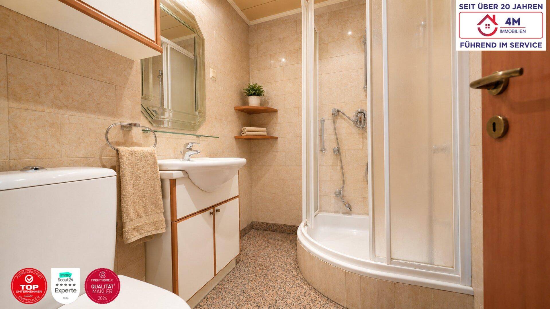 Funktionales Badezimmer mit Dusche, WC, Waschbecken und hellen Fliesen.