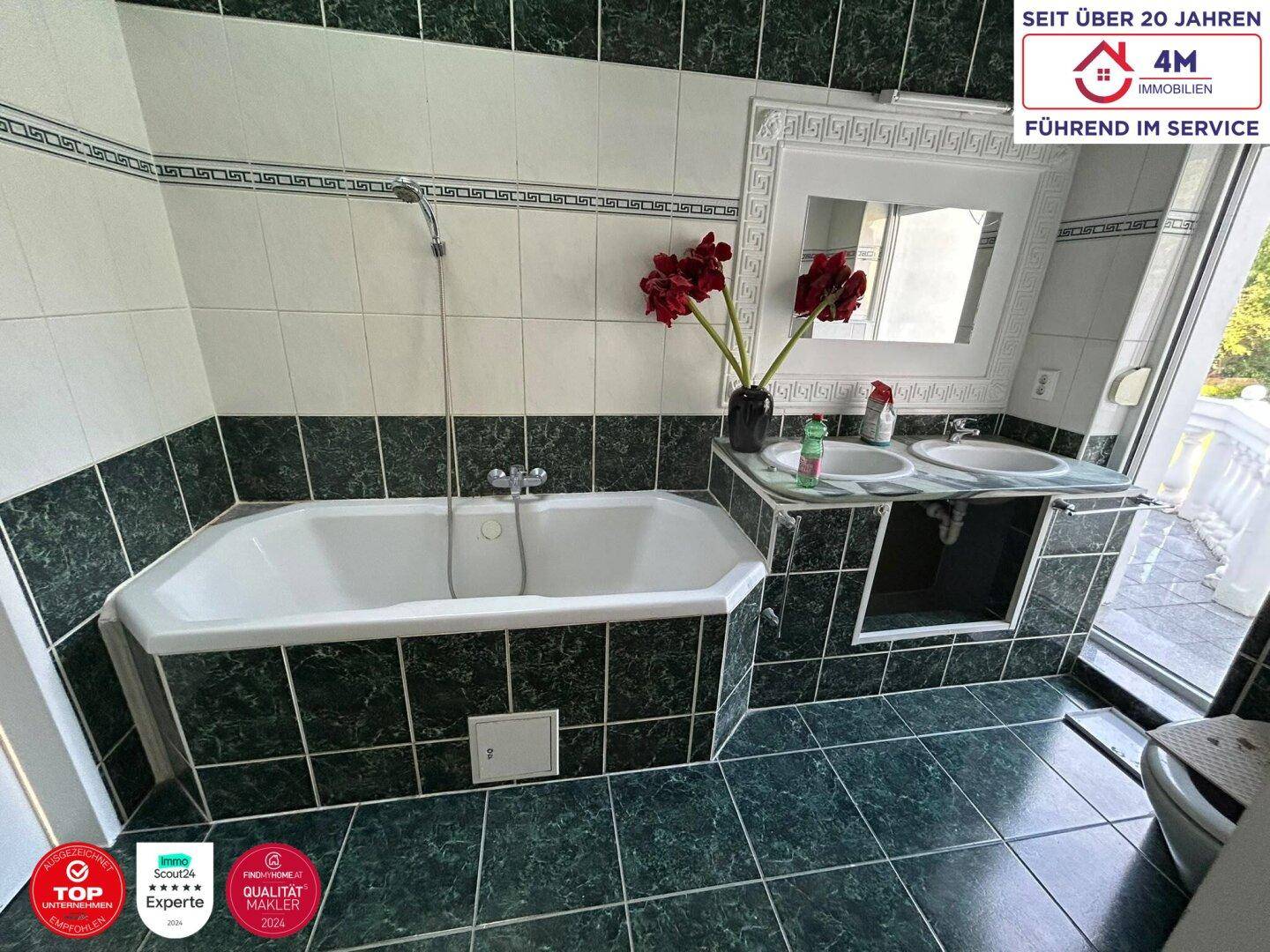 Klassisches Badezimmer mit grünen Fliesen, Badewanne und Doppelwaschbecken.