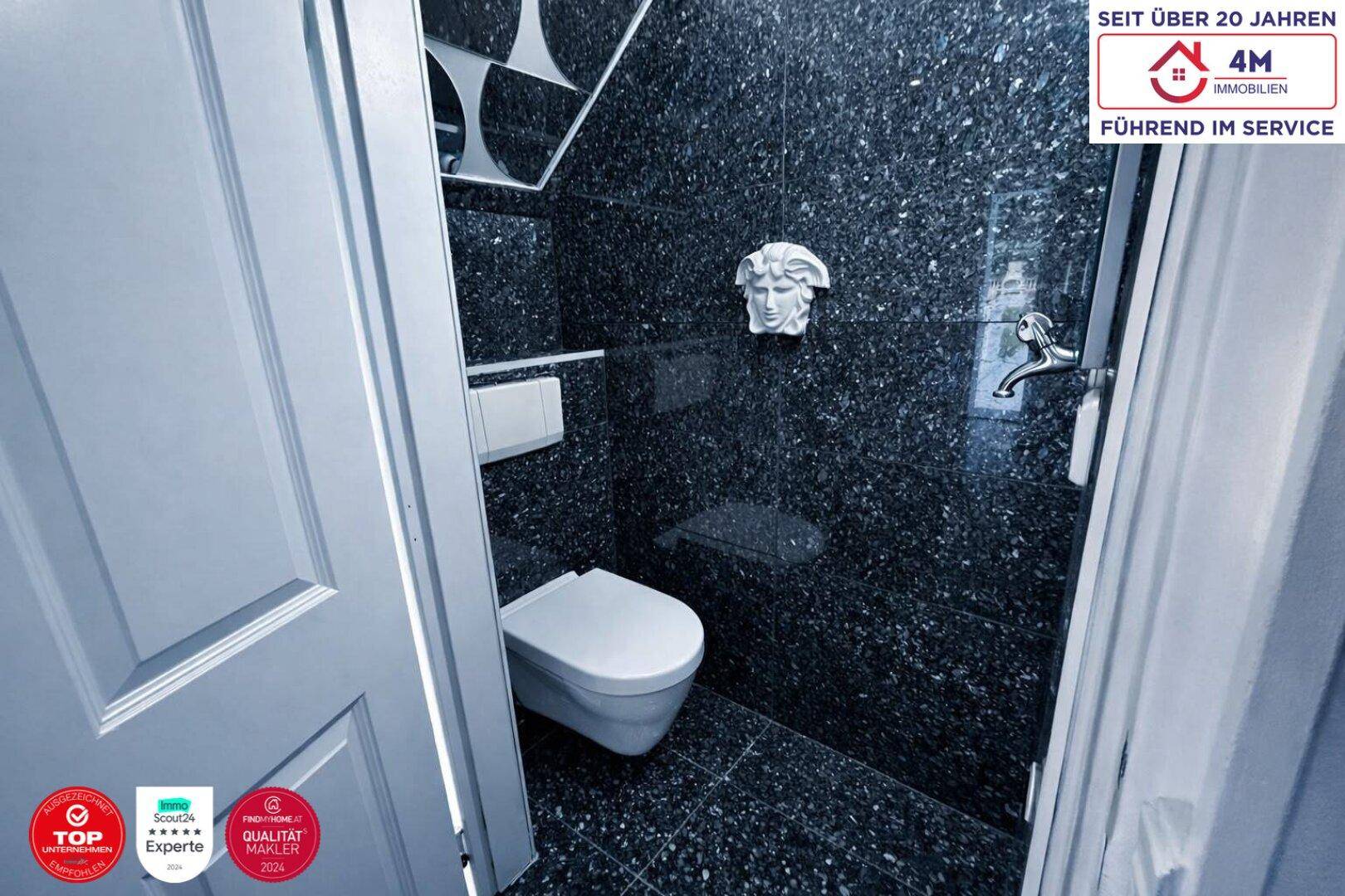 Kleines Gäste-WC mit dunklen Granitfliesen und Wand-WC.