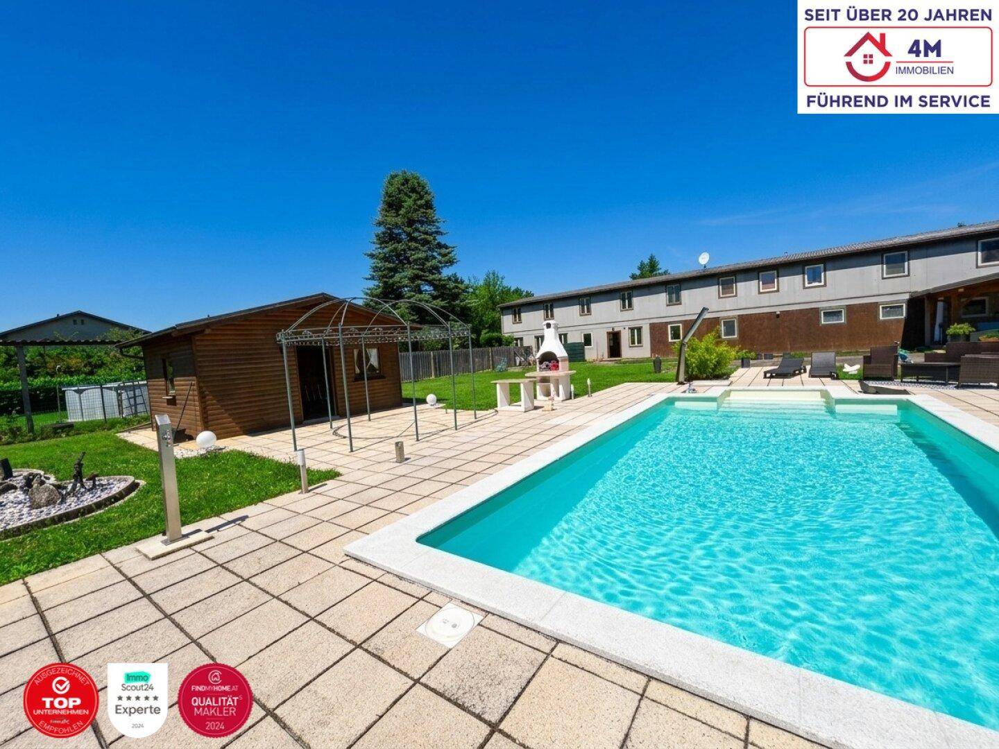 Weitläufiger Gartenbereich mit Pool, Gartenhaus und Grillstelle unter blauem Himmel.