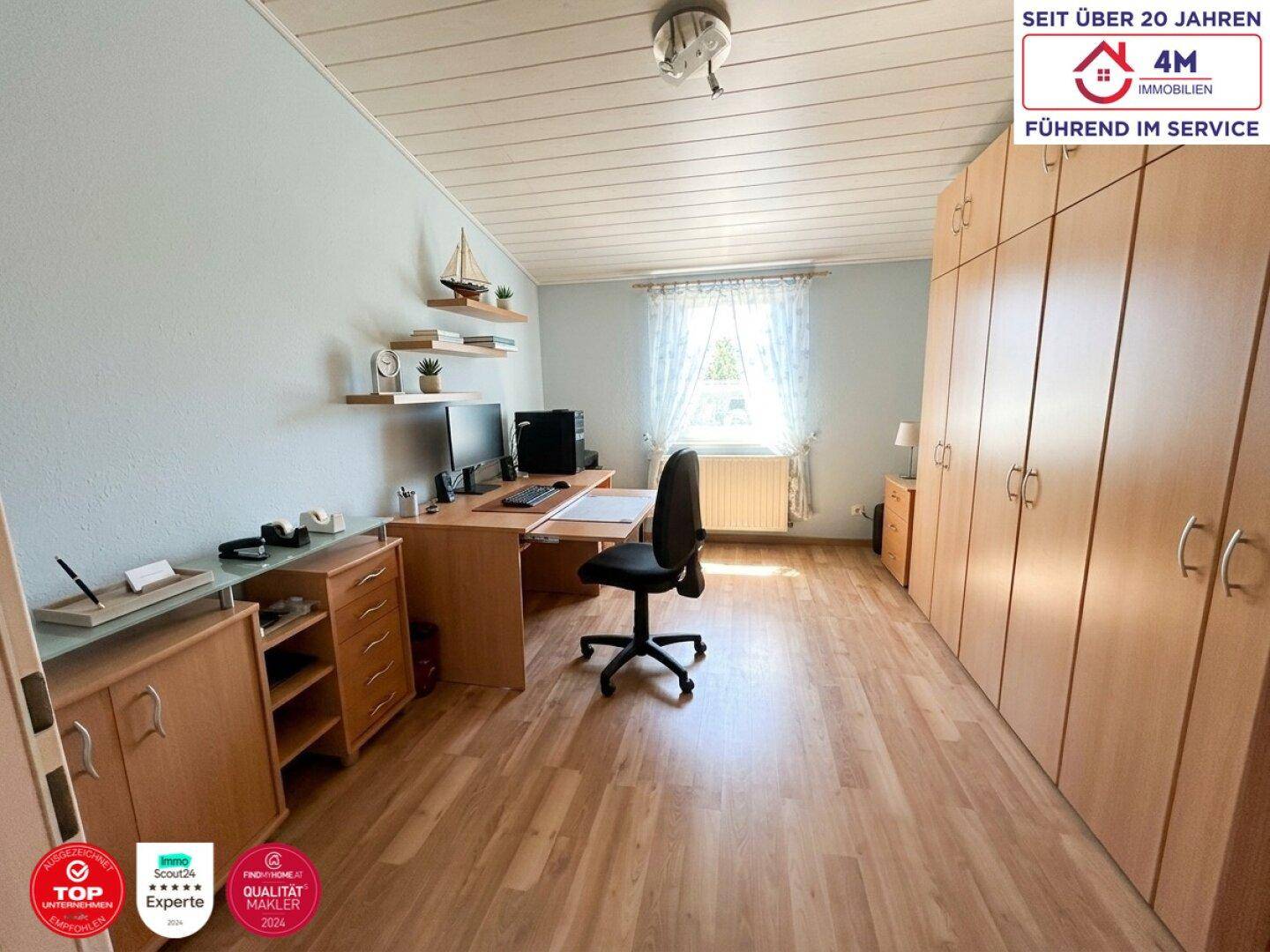 Helles Arbeitszimmer mit Holzfußboden, großem Schreibtisch und Einbauschränken.