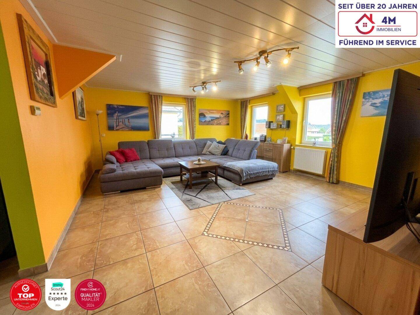 Geräumiges Wohnzimmer mit gelben Wänden, Fliesenboden und großer Eckcouch.