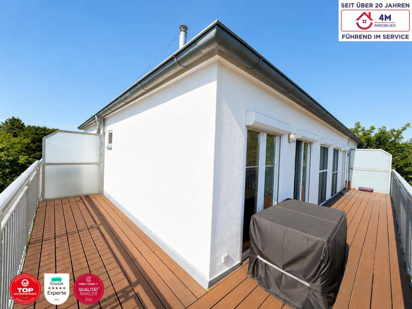 Großer Balkon mit Holzboden und weißer Fassade, bietet viel Platz im Freien.