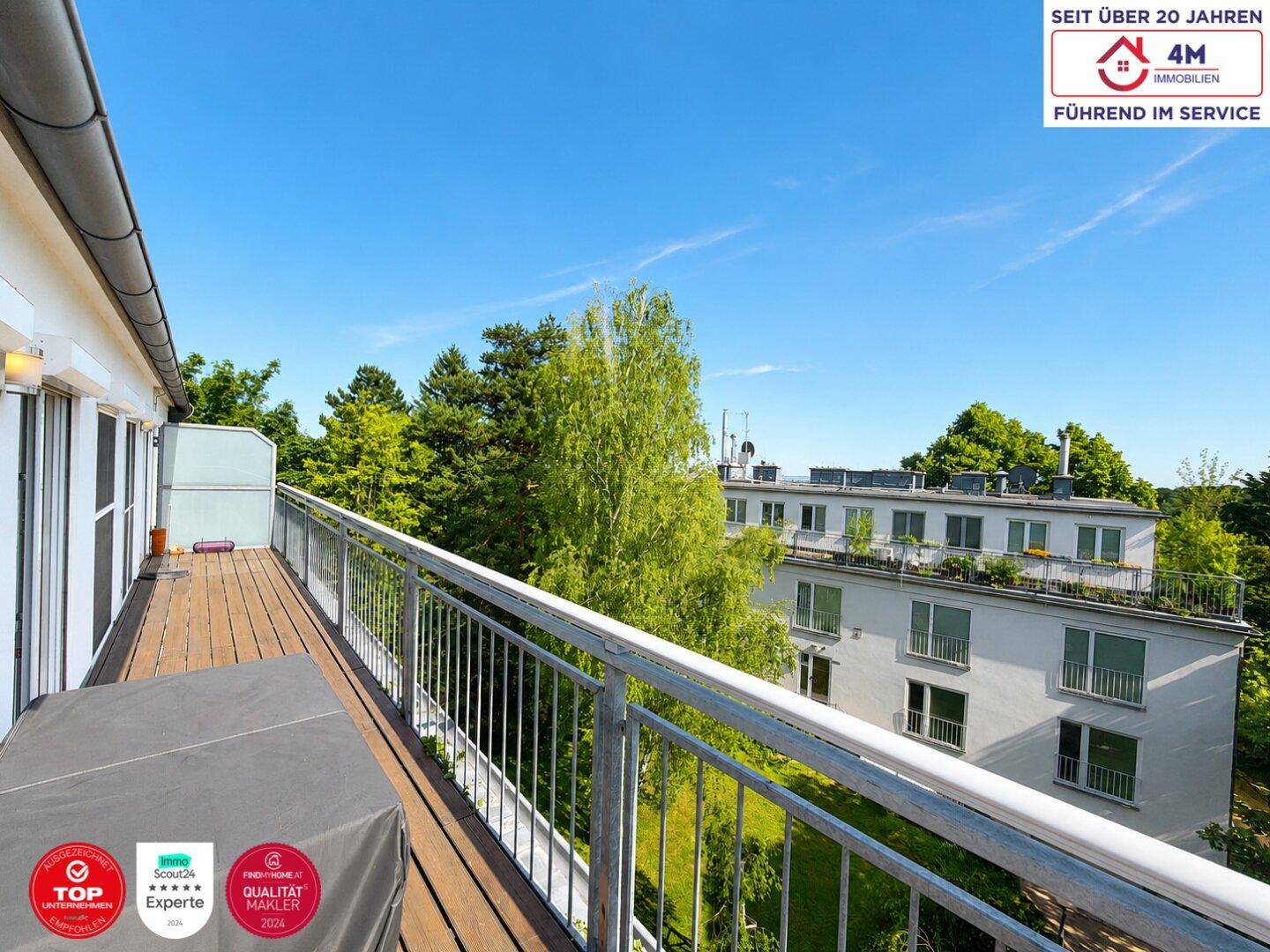 Geräumiger Balkon mit Holzboden und Blick auf die grüne Umgebung und das Nachbargebäude.