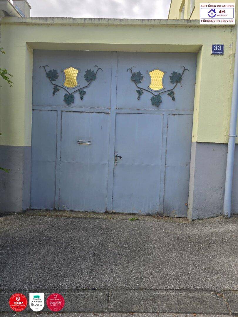 Eine alte Garagentür mit dekorativen Weinrebenmotiven und der Hausnummer 33.