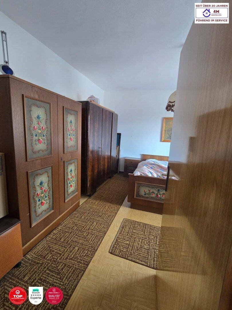 Schlafzimmer mit traditionellen Holzschränken und einem Teppichläufer auf dem Boden.