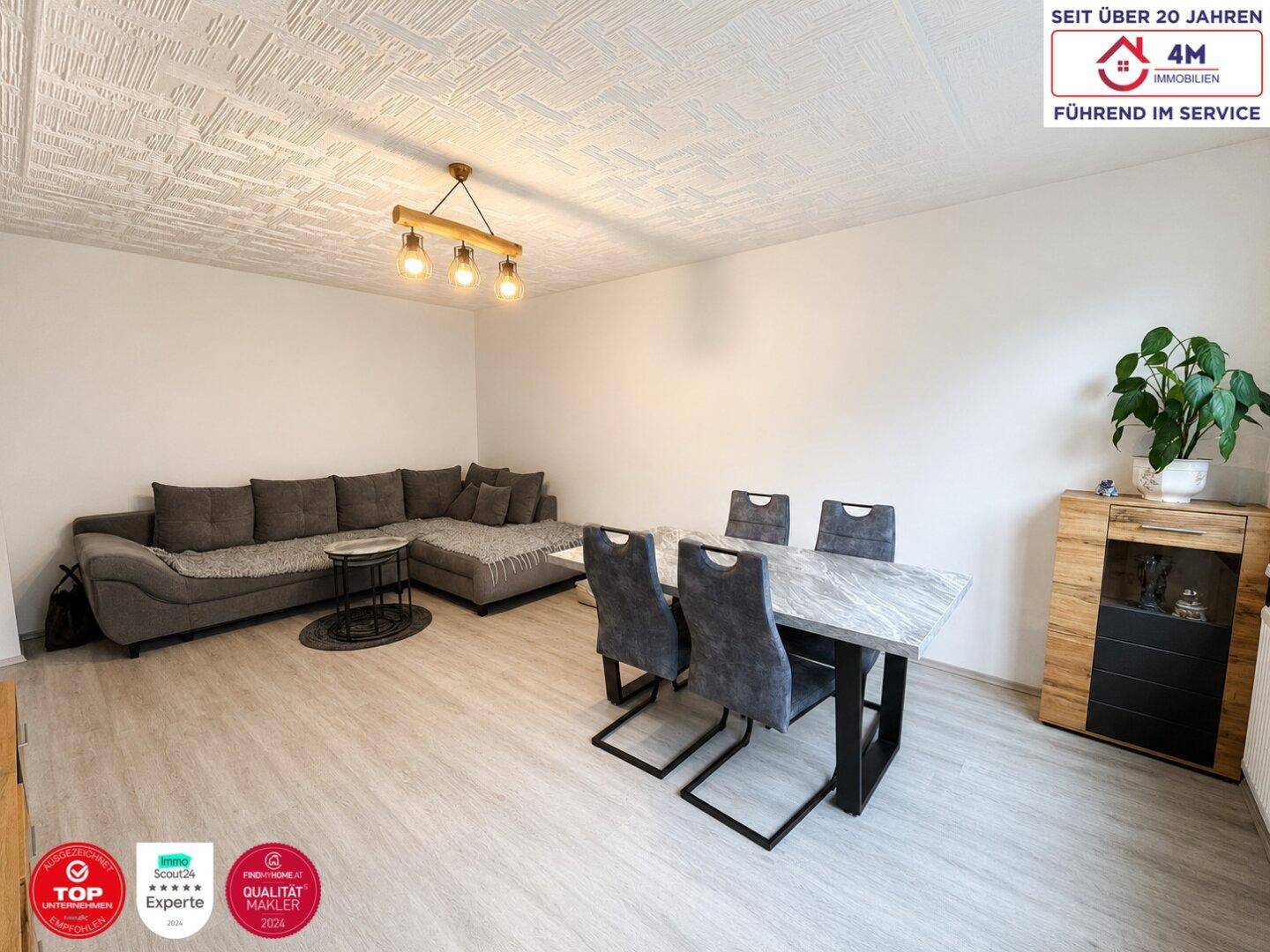 Heller Wohn-Essbereich mit Laminatboden, großem Sofa und Esstisch, ideal für Familien und Gäste.