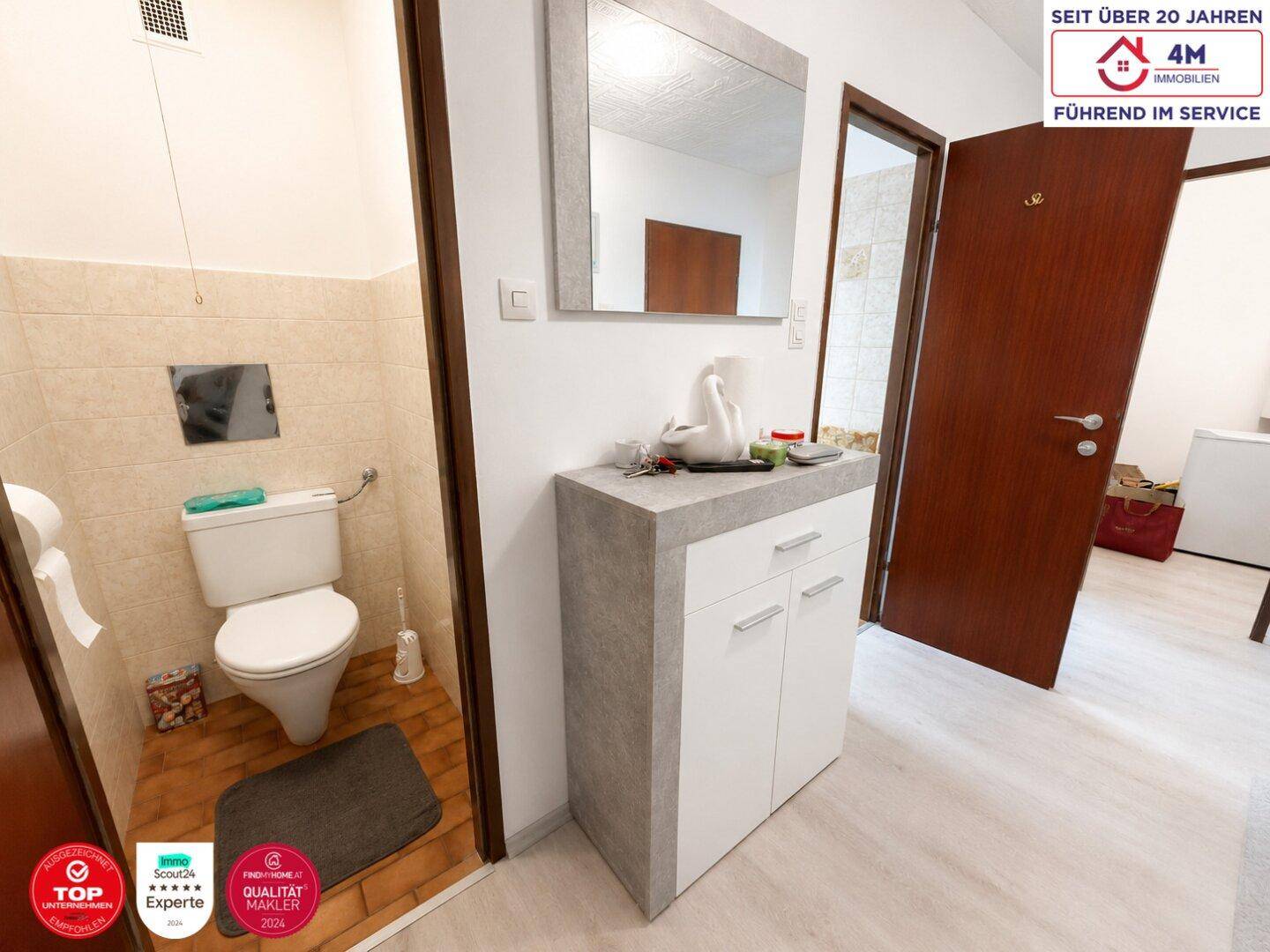 Separates WC mit wandhängender Toilette und kleinem Waschbeckenbereich im Eingangsbereich für Gäste.