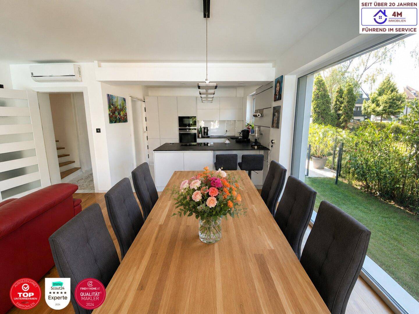 Heller offener Wohn-Essbereich mit Holztisch, modernen Stühlen und Blick in den Garten.