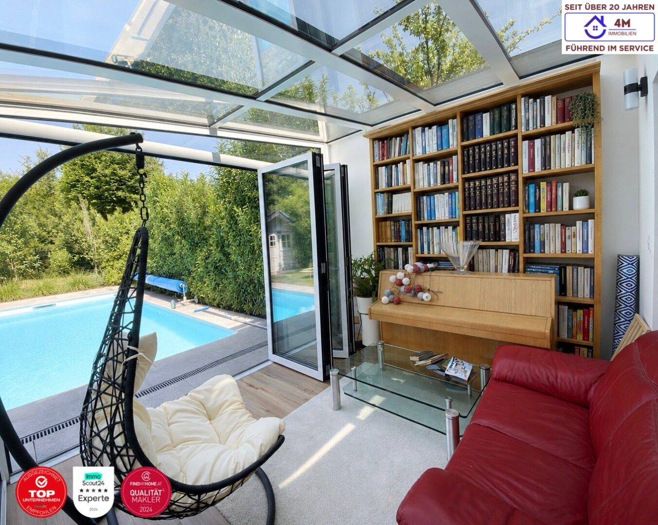 Lichtdurchfluteter Wintergarten mit Glasdach, Bücherregal, Sofa und Blick auf den Pool.