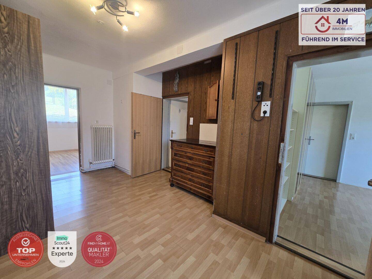 Geräumiger Flur mit Laminatboden, Holzvertäfelung und Zugang zu verschiedenen Räumen.