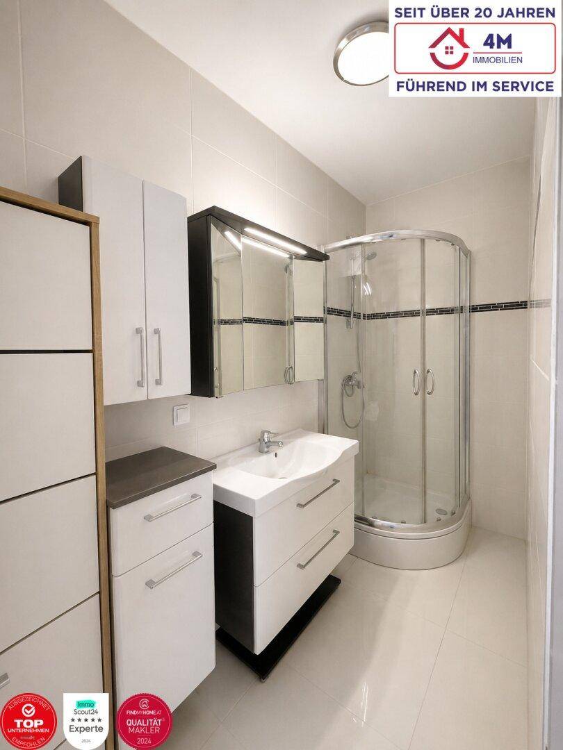 Modernes Badezimmer mit Duschkabine, Waschtisch und Spiegelschrank.