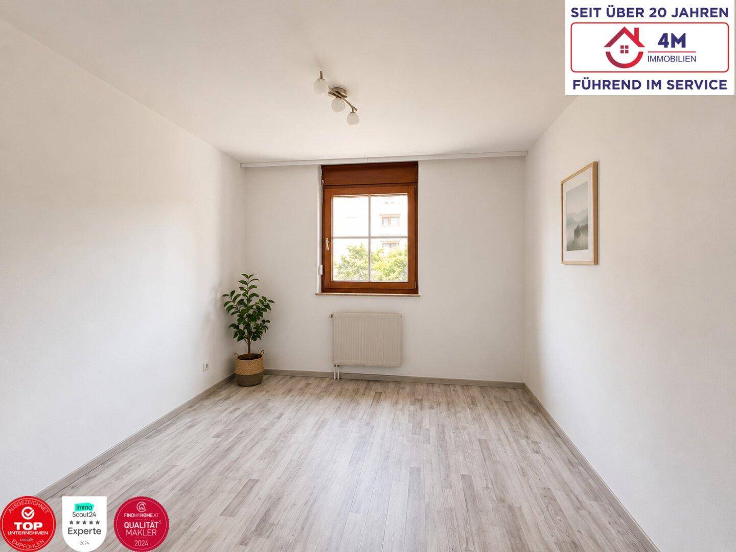 Freundliches Zimmer mit einem Fenster, hellem Boden und einfacher Dekoration.