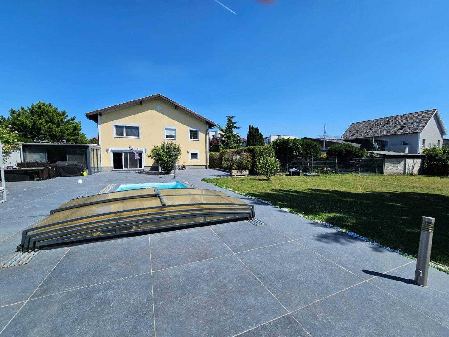 Weitläufiger Garten mit Pool, großer Rasenfläche und Blick auf das Wohnhaus.