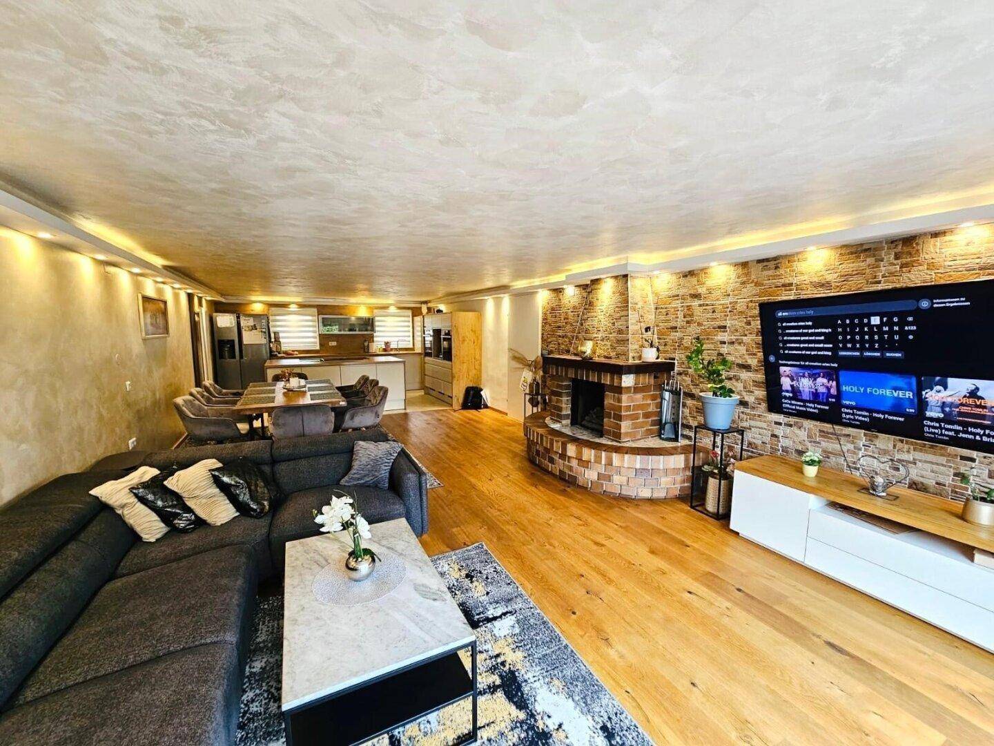 Offener Wohn- und Essbereich mit Kamin, Holzboden und moderner Einrichtung.