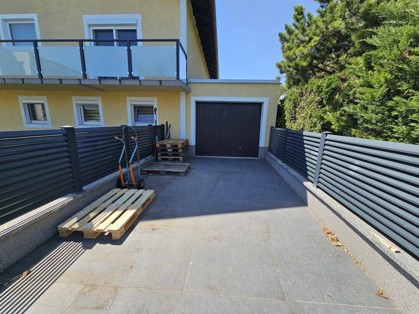 Einzelgarage mit Zufahrt und seitlichem Zaun, bietet Parkmöglichkeiten.