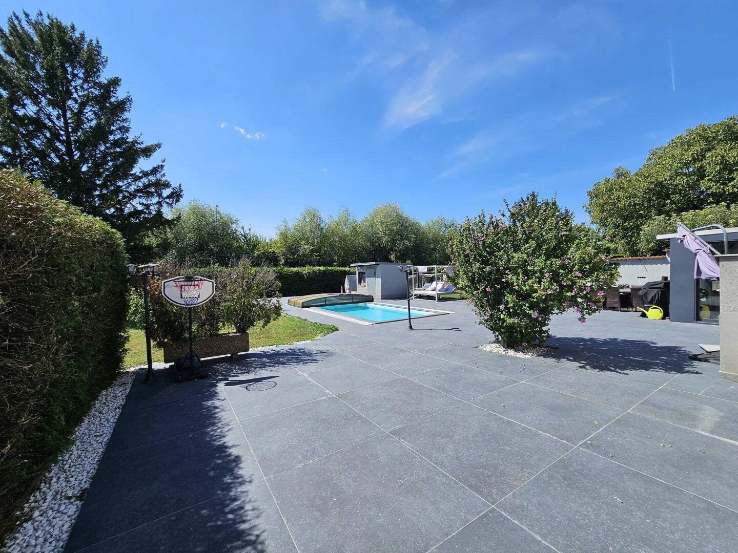 Geräumiger Garten mit Pool, Basketballkorb und viel Grünfläche für Freizeitaktivitäten.