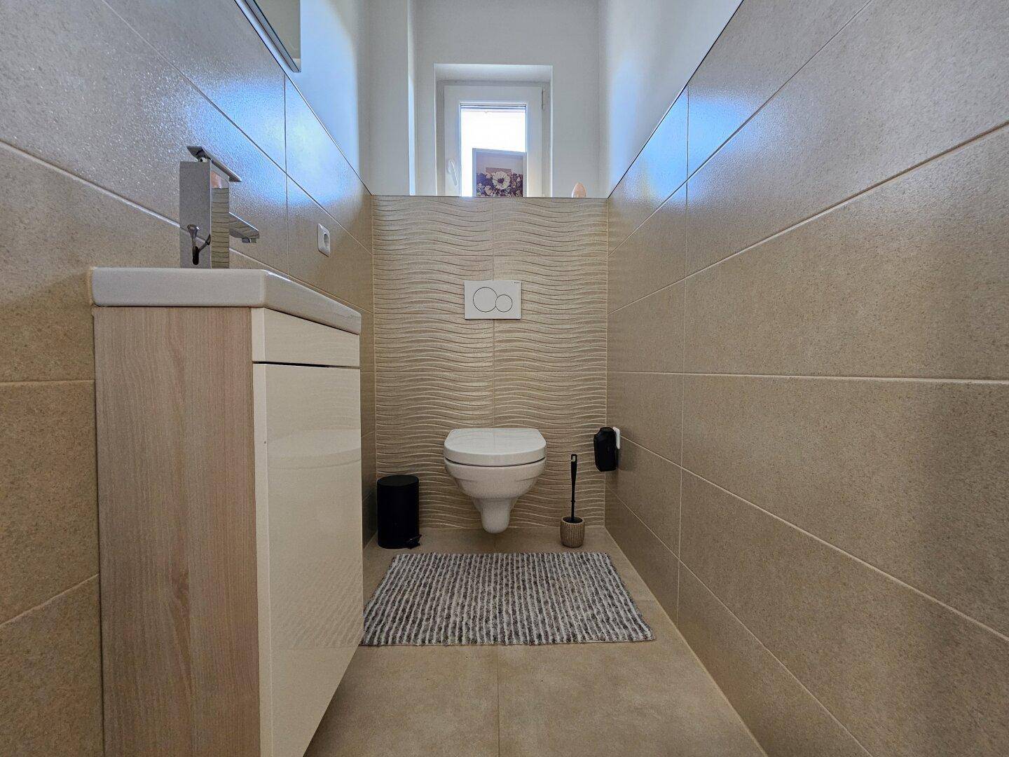 Helles Gäste-WC mit modernem Design, Wand-WC und kleinem Waschbecken.